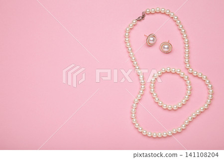 Beautiful pearl bracelet, earring, and necklace on pink background. Space for text Beautiful pearl bracelet, earring, and necklace on pink background. Space for text 141108204