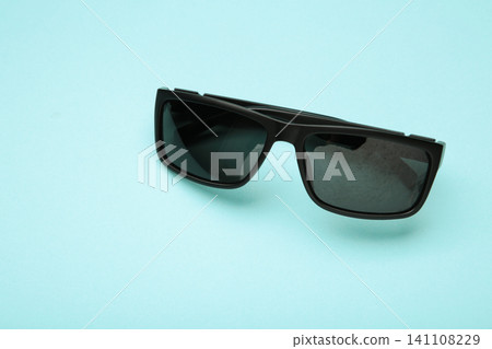 Male stylish black sunglasses on blue background. Male stylish black sunglasses on blue background. 141108229