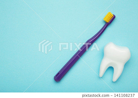 Plastic tooth with violet toothbrush on blue background. Plastic tooth with violet toothbrush on blue background. 141108237