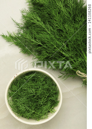 Bunch of green dill and dill on white bowl on grey background. 141108268