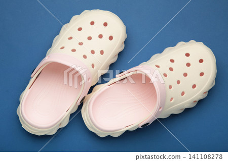 Mykolaiv, Ukraine - April 25, 2026: Couple of white Crocs sandals on dark blue background. Mykolaiv, Ukraine - April 25, 2026: Couple of white Crocs sandals on dark blue background. 141108278