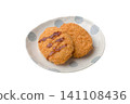 Two croquettes placed on a plate and covered in sauce. 141108436