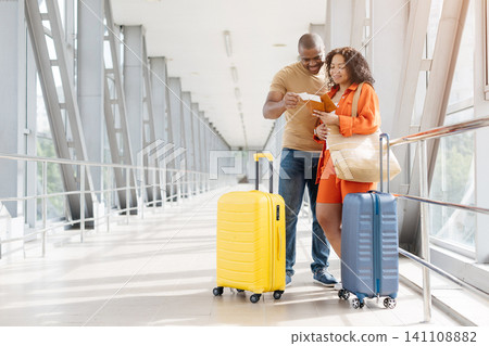 Young Black couple checking passports and boarding documents while standing in airport Young Black couple checking passports and boarding documents while standing in airport 141108882