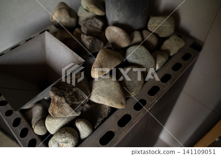 Sauna stove with heating rocks, creating steam and warm dry heat for traditional relaxation and wellness Sauna stove with heating rocks, creating steam and warm dry heat for traditional relaxation and wellness 141109051