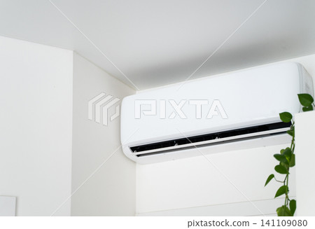 White split air conditioner unit mounted on a wall, providing cooling and comfort in a modern indoor space White split air conditioner unit mounted on a wall, providing cooling and comfort in a modern indoor space 141109080
