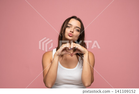 Young woman showing heart gesture with hands, blowing a kiss, expressing love, affection, and flirty charm Young woman showing heart gesture with hands, blowing a kiss, expressing love, affection, and flirty charm 141109152