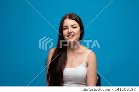 Young woman smiling with dark hair and a white tank top, portraying happiness, confidence, and a positive cheerful emotion Young woman smiling with dark hair and a white tank top, portraying happiness, confidence, and a positive cheerful emotion 141109197