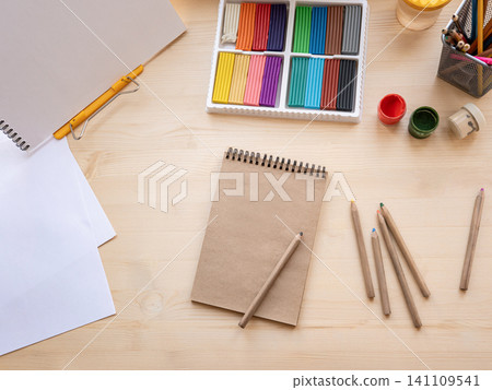 Creative workspace with pencils paints and sketchbook top view Creative workspace with pencils paints and sketchbook top view 141109541