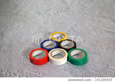 multicolored rolls of electrical tape are folded in the shape of a pyramid on a gray concrete floor multicolored rolls of electrical tape are folded in the shape of a pyramid on a gray concrete floor 141109597
