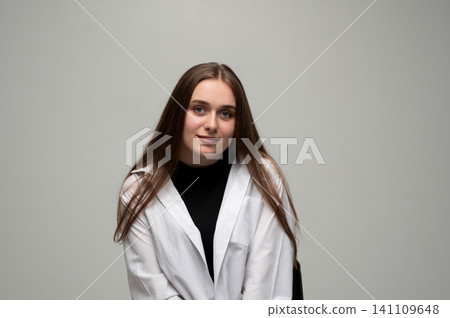 Young woman with long brown hair posing confidently in white shirt and black top, smiling at camera Young woman with long brown hair posing confidently in white shirt and black top, smiling at camera 141109648