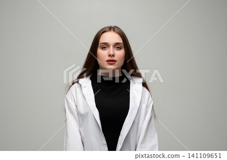 Young woman with long brown hair posing confidently in white shirt and black top, looking directly at camera Young woman with long brown hair posing confidently in white shirt and black top, looking directly at camera 141109651