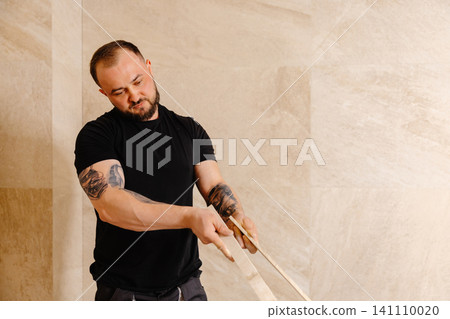 Construction worker installing ceramic tiles on bathroom wall using level tool Construction worker installing ceramic tiles on bathroom wall using level tool 141110020