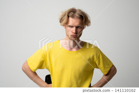Young man showing anger and frustration with sulking expression, arms akimbo, capturing concepts of mood, resentment, annoyance, and negative emotions on a light background Young man showing anger and frustration with sulking expression, arms akimbo, capturing concepts of mood, resentment, annoyance, and negative emotions on a light background 141110102