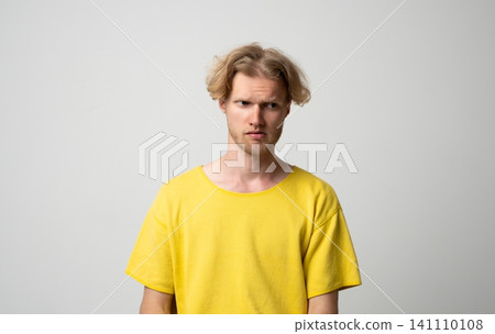 Young blond man expressing confusion, skepticism, and doubt, looking displeased and suspicious with a questioning facial expression and furrowed brows 141110108