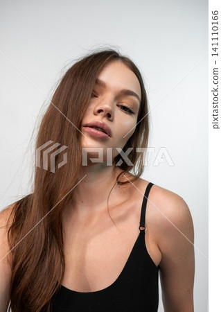 Young woman posing in a studio close-up, showcasing natural beauty, long brunette hair, and subtle makeup Young woman posing in a studio close-up, showcasing natural beauty, long brunette hair, and subtle makeup 141110166