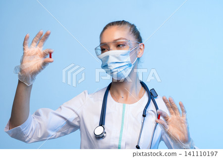 Doctor wearing medical mask and safety goggles showing red capsule, representing medicine, pharmacy, and healthcare innovation Doctor wearing medical mask and safety goggles showing red capsule, representing medicine, pharmacy, and healthcare innovation 141110197