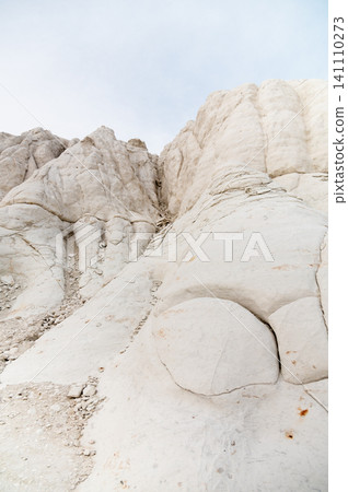 White rock formations with textured surface against a cloudy sky White rock formations with textured surface against a cloudy sky 141110273