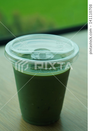 fresh matcha green tea in a clear glass on wooden floor, blur green nature background, drink, health, fresh, cool, copy space 141110708