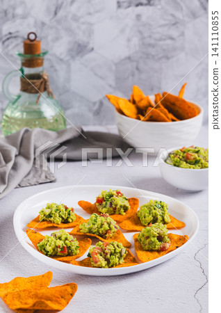 Mexican food avocado guacamole with nachos on a plate on the table vertical view Mexican food avocado guacamole with nachos on a plate on the table vertical view 141110855