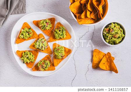 Mexican food avocado guacamole with nachos on a plate on the table top view Mexican food avocado guacamole with nachos on a plate on the table top view 141110857