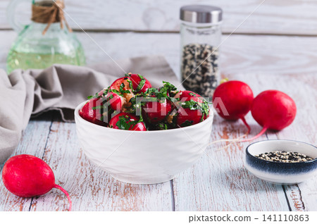 A delicious appetizer of smashed pickled radishes with herbs in a bowl on the table A delicious appetizer of smashed pickled radishes with herbs in a bowl on the table 141110863
