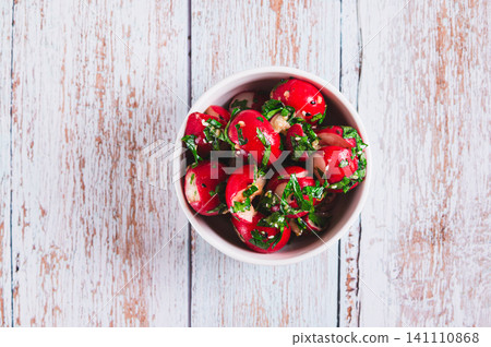 Close up of delicious appetizer of smashed pickled radishes with herbs in a bowl on the table top view 141110868
