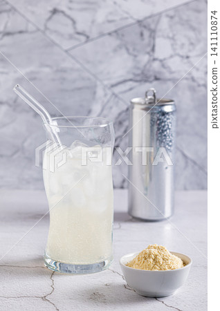 Carbonated protein drink in a glass and protein powder in a bowl on a table vertical view Carbonated protein drink in a glass and protein powder in a bowl on a table vertical view 141110874