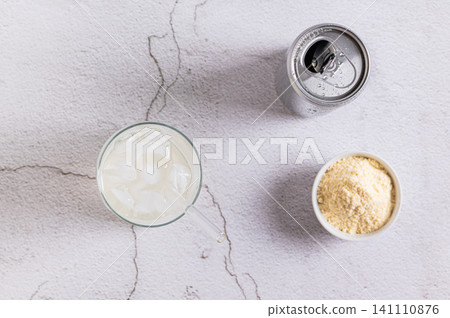 Carbonated protein drink in a glass and protein powder in a bowl on a table top view Carbonated protein drink in a glass and protein powder in a bowl on a table top view 141110876