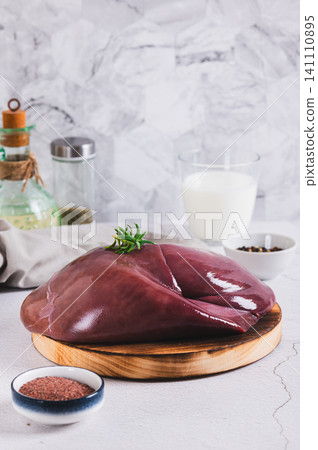 Raw whole pork liver on a wooden board on the table vertical view Raw whole pork liver on a wooden board on the table vertical view 141110895