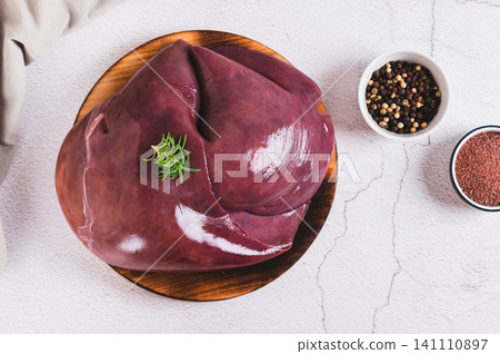 Raw whole pork liver on a wooden board on the table top view 141110897