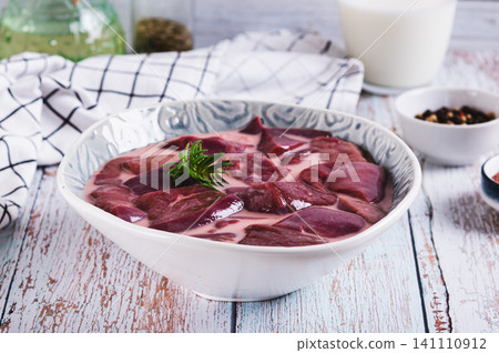 Raw pork liver soaked in milk in a bowl on the table Raw pork liver soaked in milk in a bowl on the table 141110912