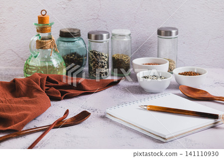 A notebook and pen for writing down recipes, spoons and spices on the kitchen table A notebook and pen for writing down recipes, spoons and spices on the kitchen table 141110930
