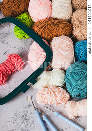 Carpet embroidery kit, skeins of colored yarn, hoops and needles on a table vertical view Carpet embroidery kit, skeins of colored yarn, hoops and needles on a table vertical view 141111015