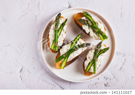 Close up of delicious sandwiches with ricotta and fresh asparagus on a plate on the table top view Close up of delicious sandwiches with ricotta and fresh asparagus on a plate on the table top view 141111027