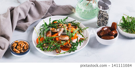 Vegetarian salad with dates, carrots, arugula and nuts on a plate on the table web banner Vegetarian salad with dates, carrots, arugula and nuts on a plate on the table web banner 141111084