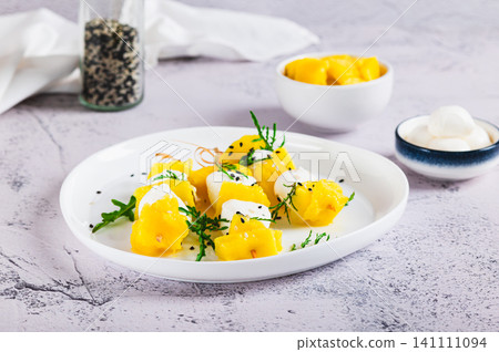 Ripe mango, mozzarella cheese, arugula and sesame seeds on skewers on a plate on the table Ripe mango, mozzarella cheese, arugula and sesame seeds on skewers on a plate on the table 141111094
