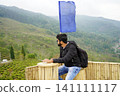 Man relaxing and enjoying mountain valley view from bamboo deck at Tinchuley in Darjeeling 141111117