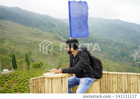 Man relaxing and enjoying mountain valley view from bamboo deck at Tinchuley in Darjeeling Man relaxing and enjoying mountain valley view from bamboo deck at Tinchuley in Darjeeling 141111117