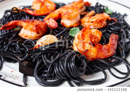 Black spaghetti with shrimp, on a white plate with a fork, on a striped napkin,marble background, homemade, no people, Black spaghetti with shrimp, on a white plate with a fork, on a striped napkin,marble background, homemade, no people, 141111198
