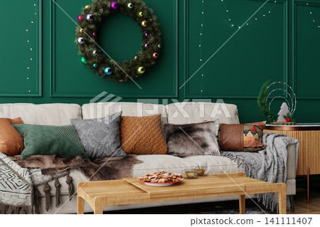 A warm living room features a sofa with colorful pillows and a green wall. A wreath hangs above, while a wooden table holds snacks. The space is lit with string lights 141111407
