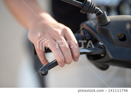 Close-up of a hand gripping the throttle of a motorcycle, showcasing the intricate details of the handlebar and control mechanisms, emphasizing the connection between rider and machine 141111746