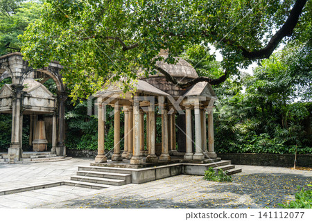 Ancient stone pavilion surrounded by lush greenery 141112077