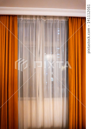Window with orange curtains in cozy room setting Window with orange curtains in cozy room setting 141112081