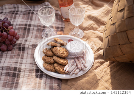 Picnic with cookies, grapes, wine and cheese on a blanket Picnic with cookies, grapes, wine and cheese on a blanket 141112394