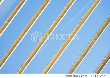 Diagonal metal bars pattern against bright clear blue sky background. Diagonal metal bars pattern against bright clear blue sky background. 141112548