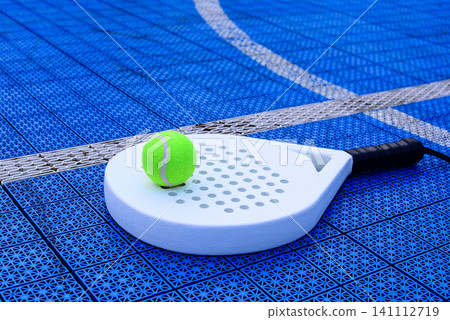 A padel racket and ball. on blue court A padel racket and ball. on blue court 141112719