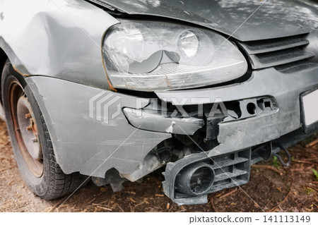 grey car shows front damage after an accident. The broken bumper and cracked headlight reveal a severe crash and collision, needing vehicle repair. grey car shows front damage after an accident. The broken bumper and cracked headlight reveal a severe crash and collision, needing vehicle repair. 141113149
