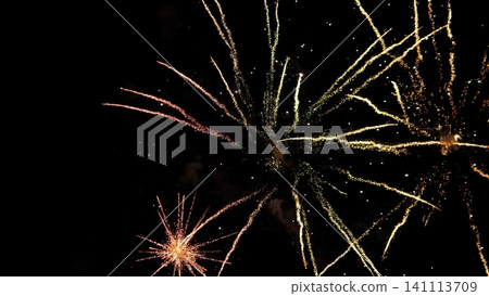 Golden and orange fireworks explode across dark night sky, sending sparkling trails and glowing embers in many directions for festive celebration, holiday event, and vivid Golden and orange fireworks explode across dark night sky, sending sparkling trails and glowing embers in many directions for festive celebration, holiday event, and vivid 141113709