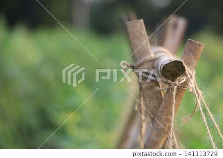 A close-up view of a wooden fence post with rope in a blurred green field A close-up view of a wooden fence post with rope in a blurred green field 141113729