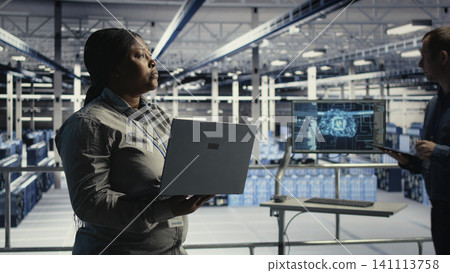 Data center administrator uses a laptop to monitor deep learning processes, working with AI technology and high performance systems. Data center administrator uses a laptop to monitor deep learning processes, working with AI technology and high performance systems. 141113758